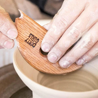 A wood potter's rib with a curved arc, straight edge, and unique V- and U-shaped notches for shaping clay. Amaranth Stoneware Canada.